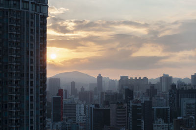 Modern buildings in city against sky during sunset