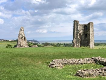 Stone structure on field against cloudy sky