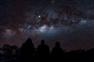 Rear view of silhouette men standing against sky at night