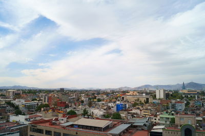 View of cityscape against cloudy sky