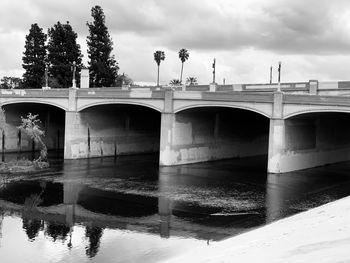 Arch bridge over river against sky