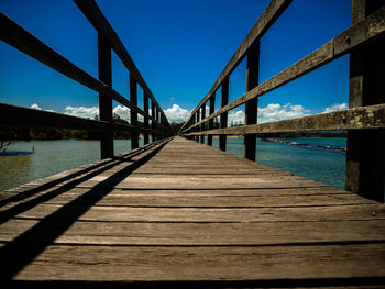 Surface level of footbridge against blue sky