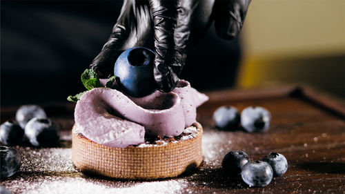 Cropped hand of woman wearing glove preparing dessert