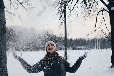 Woman playing with snow while standing outdoors