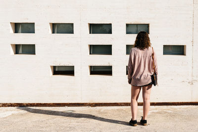 Rear view of woman standing against building