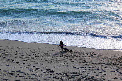 High angle view of boy walking with surfboard at beach