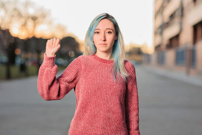 Portrait of smiling young woman gesturing while standing on street