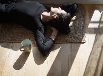 High angle view of woman lying on mat at home