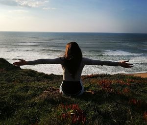 Rear view of woman on beach against sky during sunset