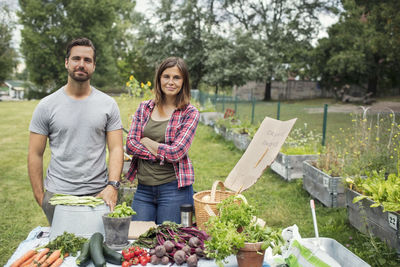 Portrait of mid adult couple standing at table full of freshly harvested garden vegetables