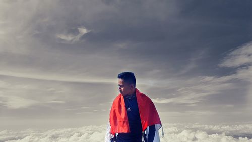 Full length of teenage boy looking away against sky