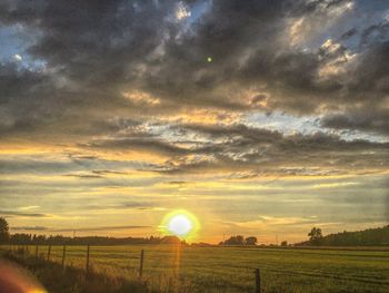 Scenic view of grassy field against sky at sunset