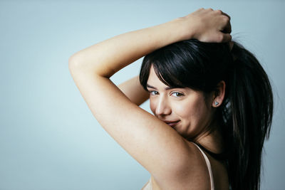 Portrait of young woman standing against gray background