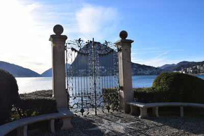 Railing by lake against sky