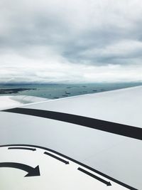 Cropped image of airplane wing flying against sea