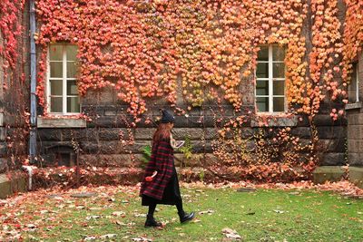 Rear view of woman with umbrella walking on autumn leaves