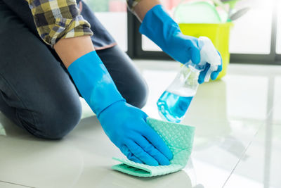 Midsection of woman cleaning floor at home