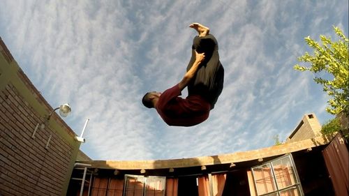 Low angle view of woman jumping against sky