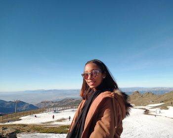 Portrait of smiling young woman against sky during winter