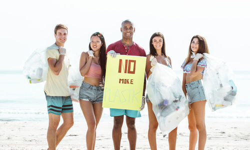 Portrait of activist holding plastic bags while standing at beach