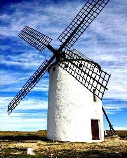 Traditional windmill on field against sky