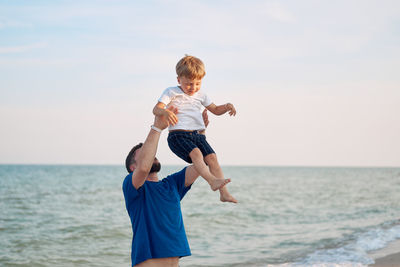 Rear view of father and daughter in sea against sky