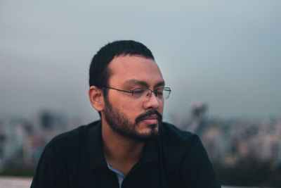 Portrait of young man looking away against sky