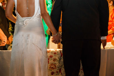 Rear view of bride and groom holding hands during wedding ceremony