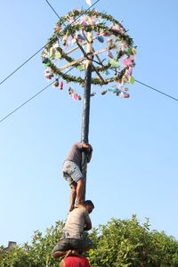 Low angle view of man against trees against clear blue sky