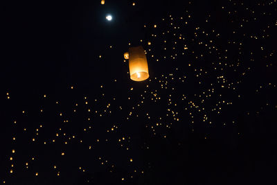 Low angle view of illuminated lantern against black sky