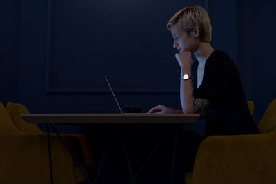 Side view of man using mobile phone while sitting on table