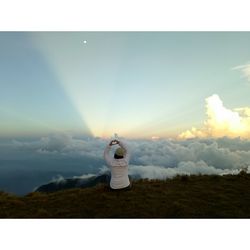 Man on cross against sky during sunset