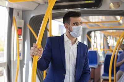 Young man in suit and mask using public transport