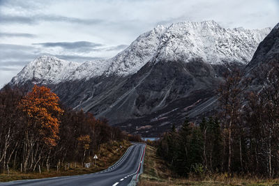 Road amidst snowcapped mountains against sky