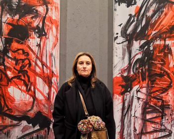 Portrait of woman standing against graffiti wall