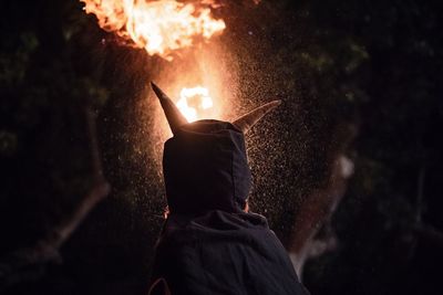 Rear view of person wearing costume while standing against fire