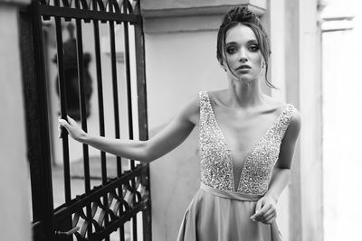 Portrait of woman standing against railing