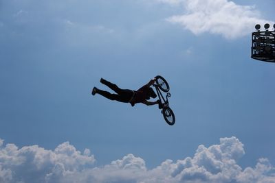 Low angle view of man paragliding against blue sky
