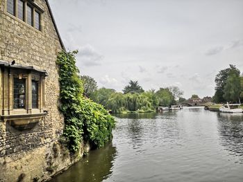 Scenic view of river by buildings against sky