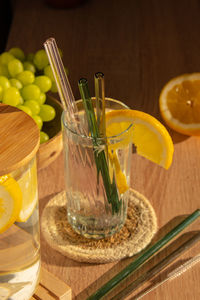 Glass of water with fresh lemon juice with reusable glass straws detox cold tonic water with sunny