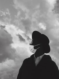 Portrait of person wearing corona face mask standing against sky