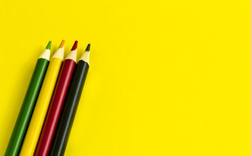 High angle view of colored pencils against yellow background