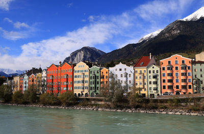 Buildings by river against sky