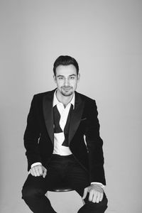Portrait of young man sitting against white background