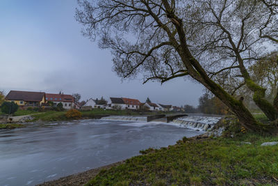 Scenic view of river by buildings against sky