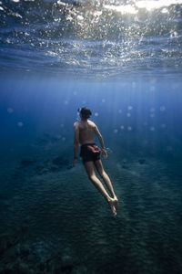 Shirtless young man swimming underwater in sea