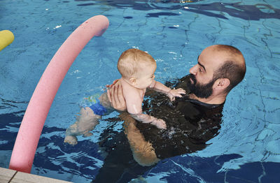 High angle view of man playing with son in swimming pool