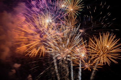 Firework display over river against sky at night