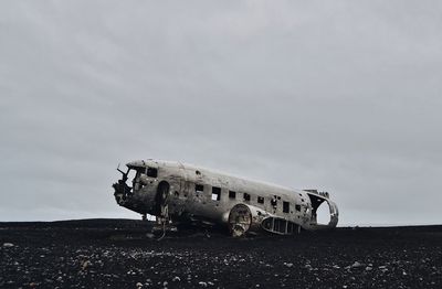 Abandoned airplane on airport runway against sky