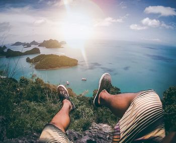 Low section of man relaxing against calm blue sea